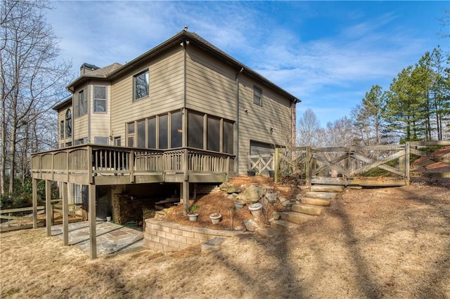 back of property featuring a wooden deck, a garage, and a sunroom