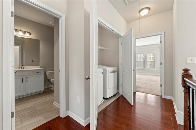 hallway with sink, washer and dryer, and light wood-type flooring