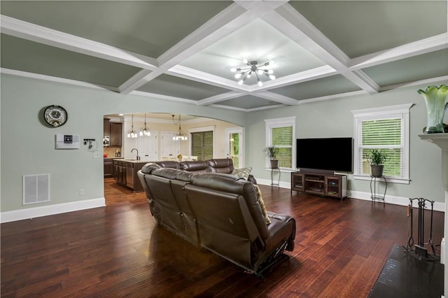 living room featuring dark wood-type flooring, beamed ceiling, coffered ceiling, and a notable chandelier