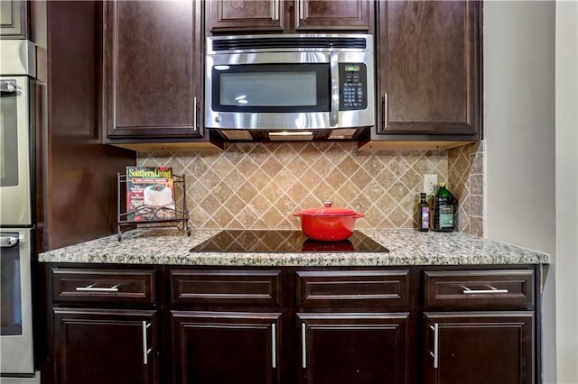 kitchen featuring stainless steel appliances, tasteful backsplash, and light stone counters