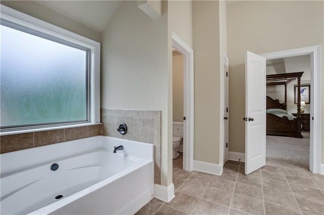 bathroom with toilet, a bath, lofted ceiling, and tile patterned floors