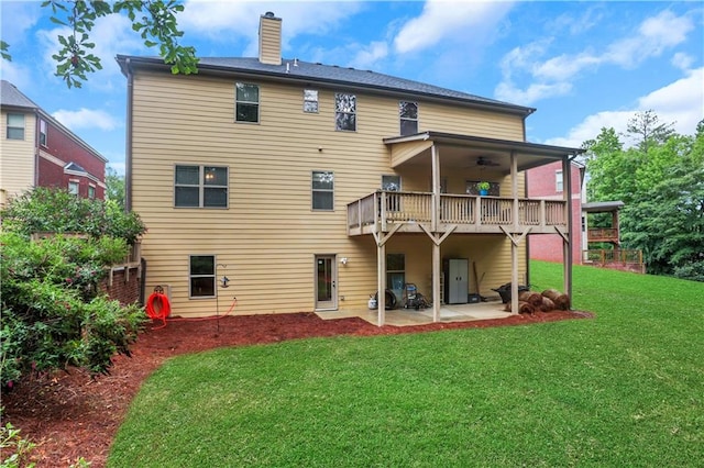 rear view of property with a deck, ceiling fan, a yard, and a patio area