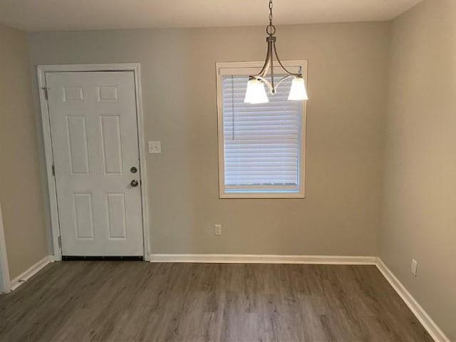 spare room featuring a notable chandelier and dark hardwood / wood-style floors