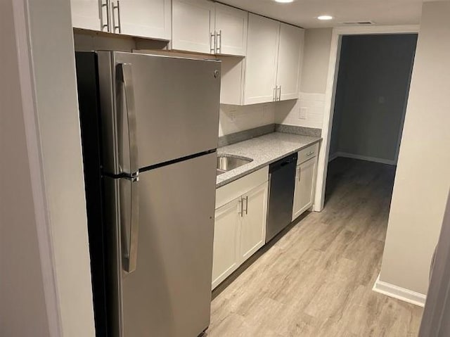 kitchen with light hardwood / wood-style floors, dishwasher, backsplash, white cabinetry, and stainless steel fridge