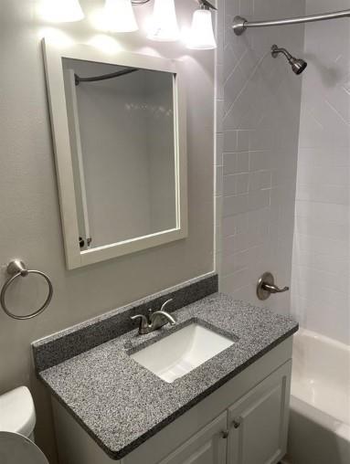 full bathroom with tiled shower / bath, toilet, and vanity