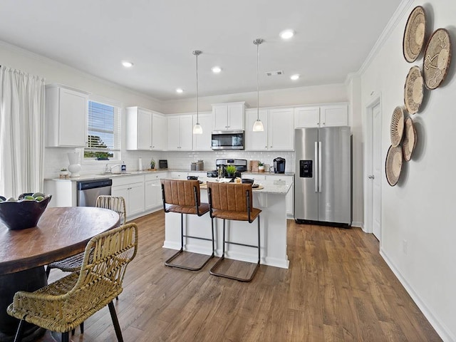 kitchen with a kitchen island, light countertops, appliances with stainless steel finishes, dark wood-style floors, and white cabinetry