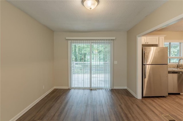 4669 Birch Ridge Trl, Stone Mountain, GA 30083 - kitchen featuring appliances with stainless steel finishes, wood finished floors, white cabinetry, a textured ceiling, and baseboards