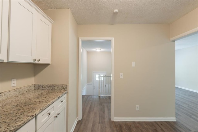 4669 Birch Ridge Trl, Stone Mountain, GA 30083 - kitchen with dark wood-style floors, white cabinets, baseboards, light stone countertops, and a textured ceiling