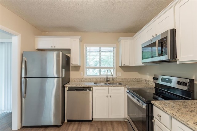 4669 Birch Ridge Trl, Stone Mountain, GA 30083 - kitchen featuring stainless steel appliances, a sink, wood finished floors, white cabinetry, and a textured ceiling