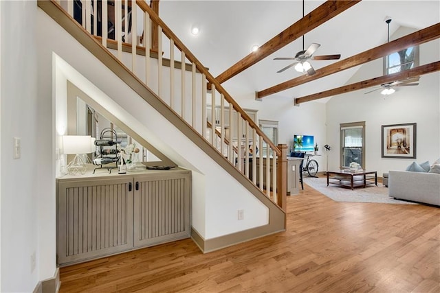 stairs with hardwood / wood-style flooring, ceiling fan, high vaulted ceiling, and beamed ceiling