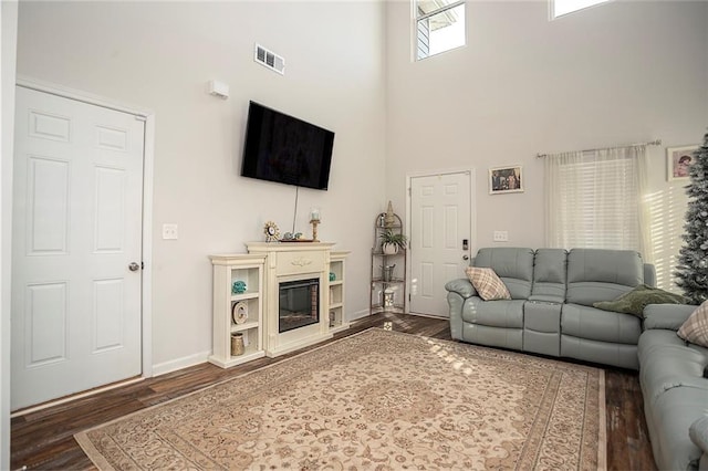 living room featuring a high ceiling and dark wood-type flooring