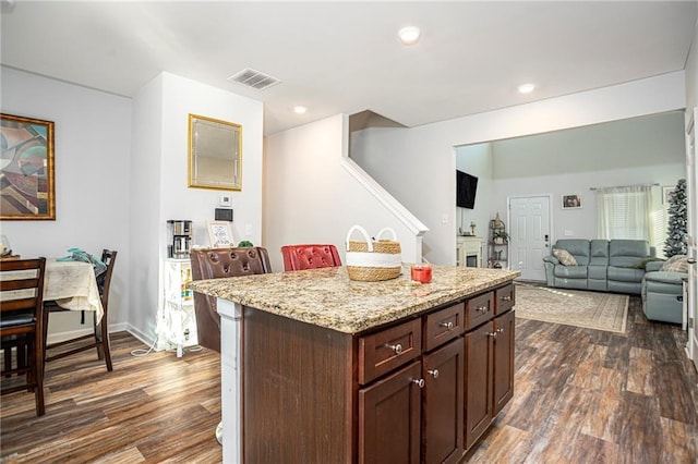 kitchen featuring a kitchen island, light stone counters, dark brown cabinets, and dark hardwood / wood-style floors