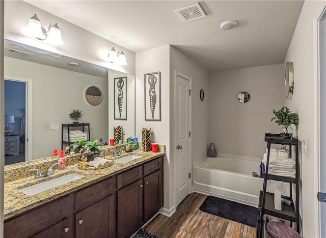 bathroom with wood-type flooring, vanity, and a tub to relax in