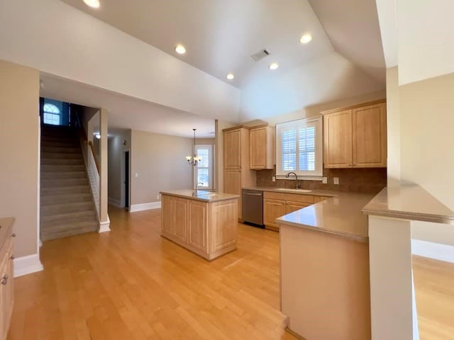 kitchen featuring a kitchen island, a sink, vaulted ceiling, stainless steel dishwasher, and light brown cabinetry