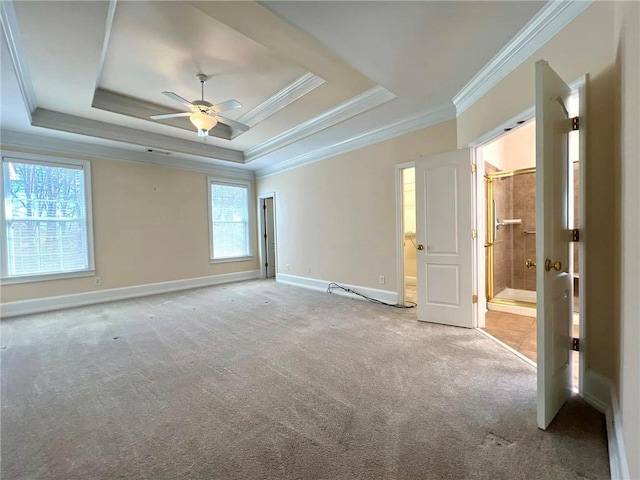 empty room featuring light carpet, baseboards, a raised ceiling, and crown molding