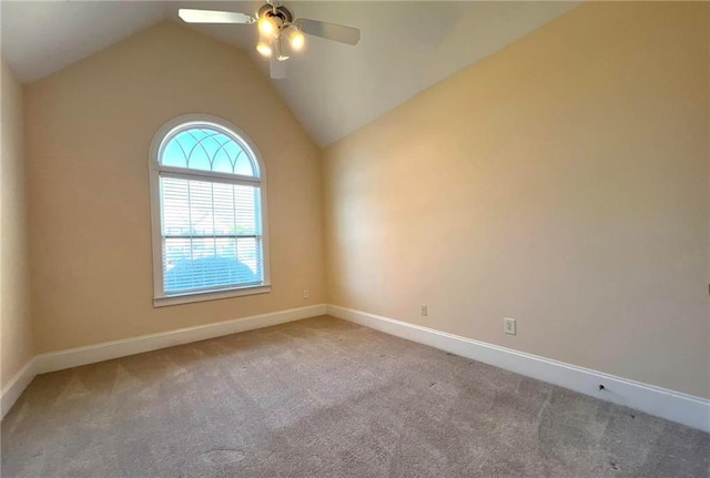 carpeted empty room with vaulted ceiling, baseboards, and ceiling fan