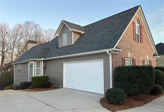 view of property exterior featuring a garage, driveway, roof with shingles, and brick siding