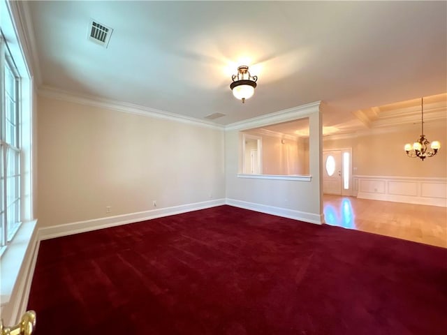 empty room featuring a notable chandelier, dark colored carpet, visible vents, and crown molding