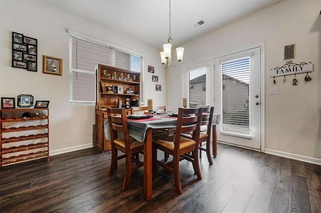 dining space with dark wood-type flooring, visible vents, a healthy amount of sunlight, and a chandelier