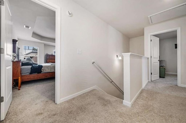 hall featuring attic access, carpet flooring, an upstairs landing, visible vents, and baseboards