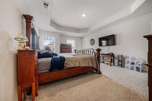 carpeted bedroom with visible vents and a tray ceiling