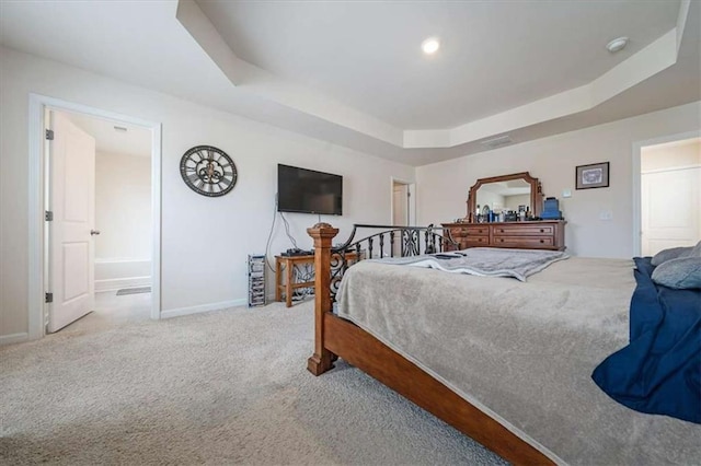 bedroom featuring ensuite bathroom, carpet flooring, a tray ceiling, and baseboards