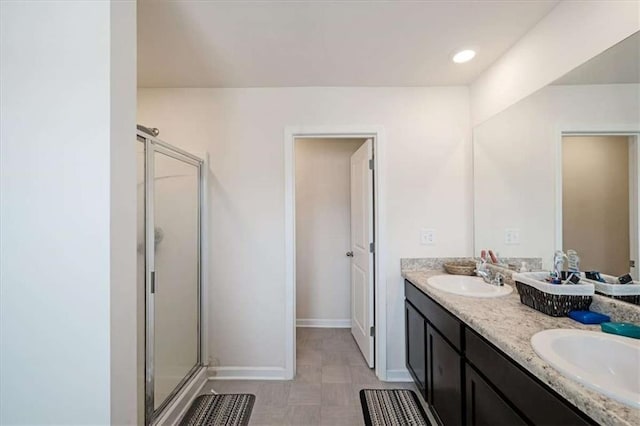 full bath featuring double vanity, a shower stall, and a sink