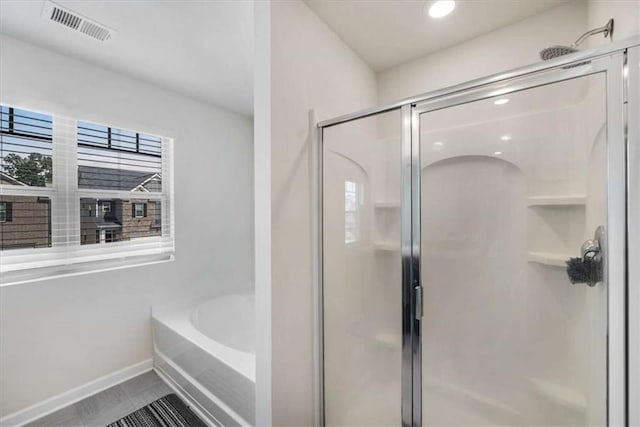bathroom with tile patterned floors, a shower stall, baseboards, visible vents, and a garden tub