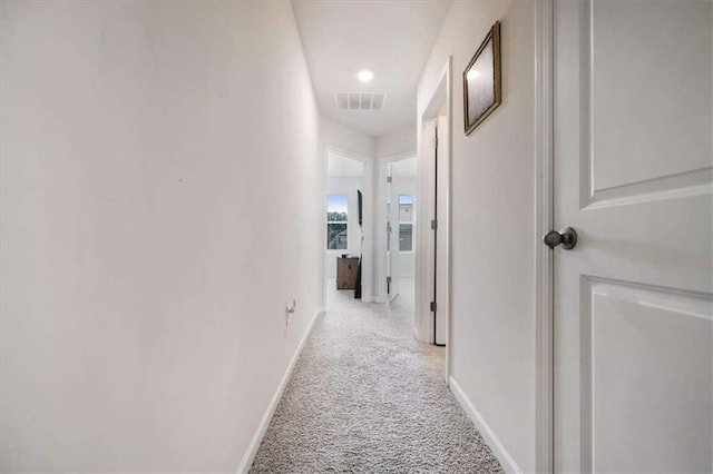 corridor with visible vents, carpet, and baseboards