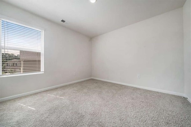 carpeted spare room featuring visible vents and baseboards