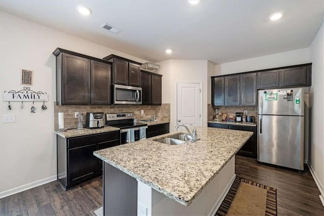 kitchen featuring decorative backsplash, a sink, appliances with stainless steel finishes, dark brown cabinets, and dark wood finished floors