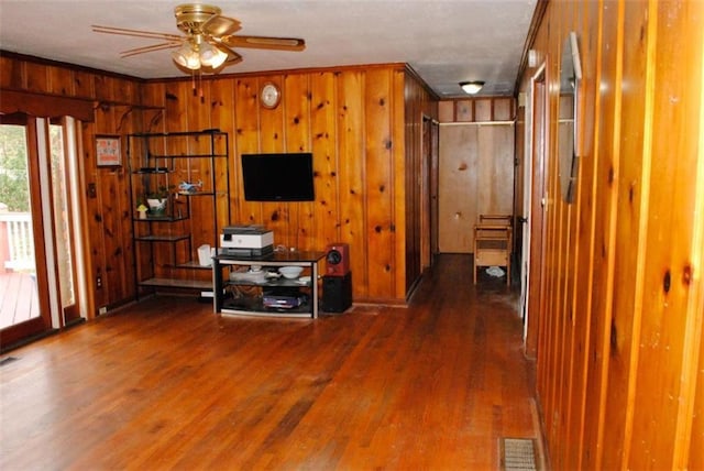 unfurnished living room with ceiling fan, crown molding, dark hardwood / wood-style floors, and wood walls