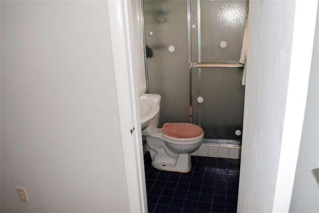 bathroom with toilet, tile patterned flooring, and a shower with door