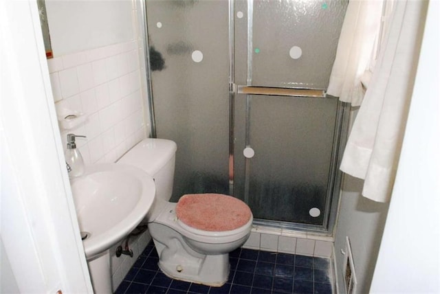 bathroom featuring a shower with shower door, tile walls, tile patterned flooring, and toilet