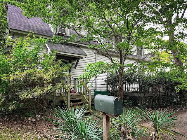 view of side of home with roof with shingles and a wooden deck