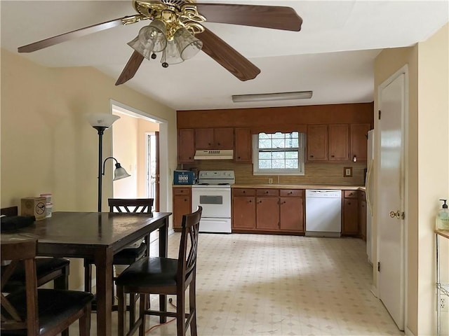 kitchen with a ceiling fan, brown cabinets, a sink, under cabinet range hood, and white appliances