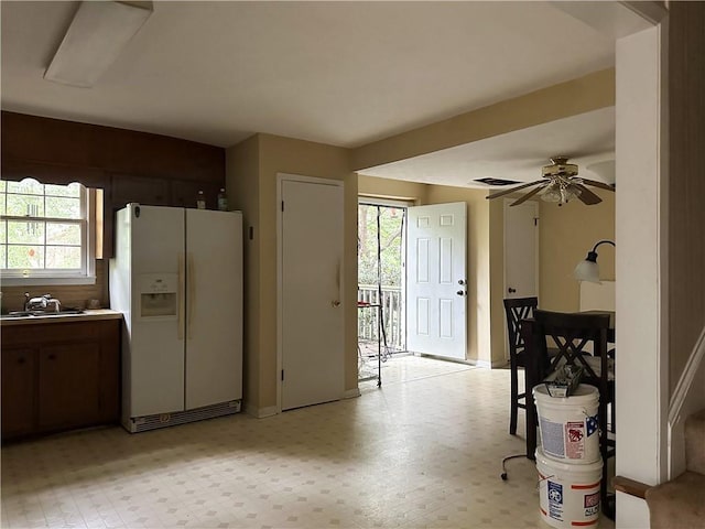 kitchen with ceiling fan, a sink, white fridge with ice dispenser, and light floors