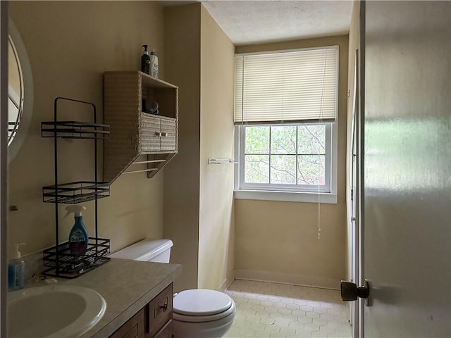 bathroom featuring vanity, toilet, baseboards, a textured ceiling, and tile patterned floors