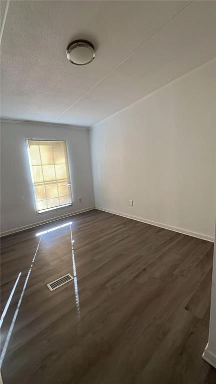 empty room with a textured ceiling and dark hardwood / wood-style floors