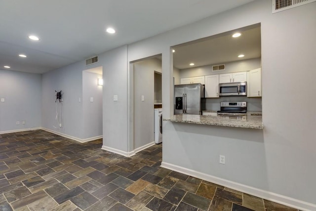 kitchen with white cabinets, light stone countertops, kitchen peninsula, and appliances with stainless steel finishes