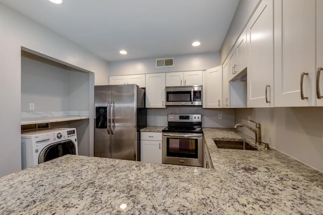 kitchen featuring sink, white cabinets, stainless steel appliances, and washer / dryer