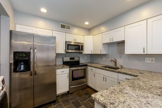 kitchen featuring light stone counters, sink, white cabinets, and appliances with stainless steel finishes