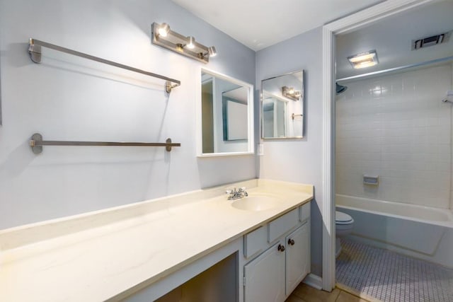 full bathroom featuring tile patterned floors, vanity, tiled shower / bath, and toilet