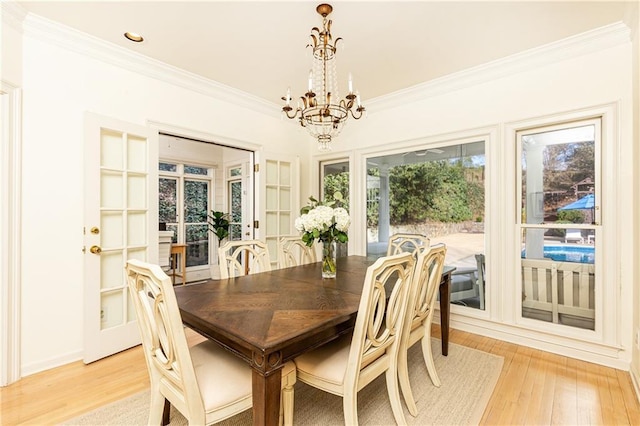 dining space featuring ornamental molding, light wood-style flooring, and a notable chandelier