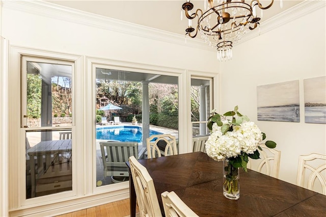 dining room featuring crown molding, a chandelier, plenty of natural light, and wood finished floors