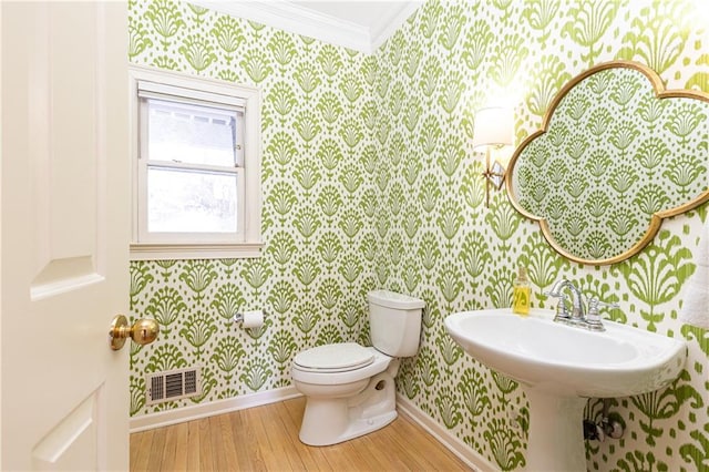 half bathroom featuring toilet, wallpapered walls, visible vents, and baseboards