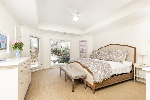 bedroom featuring a ceiling fan, a tray ceiling, crown molding, and light colored carpet