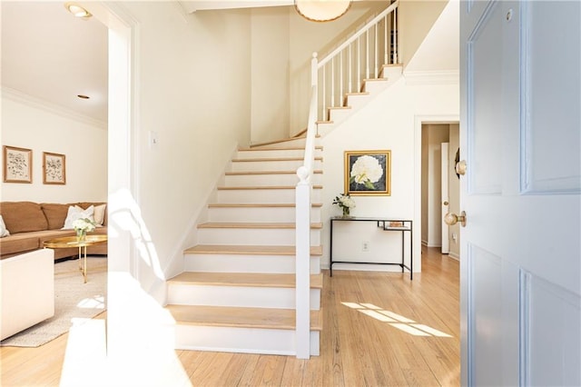 stairs featuring baseboards, crown molding, and wood finished floors