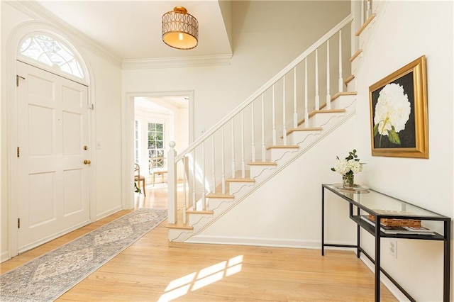 foyer entrance with baseboards, stairway, wood finished floors, and crown molding