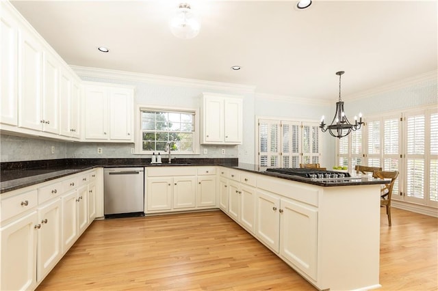 kitchen with a peninsula, a sink, appliances with stainless steel finishes, light wood finished floors, and crown molding